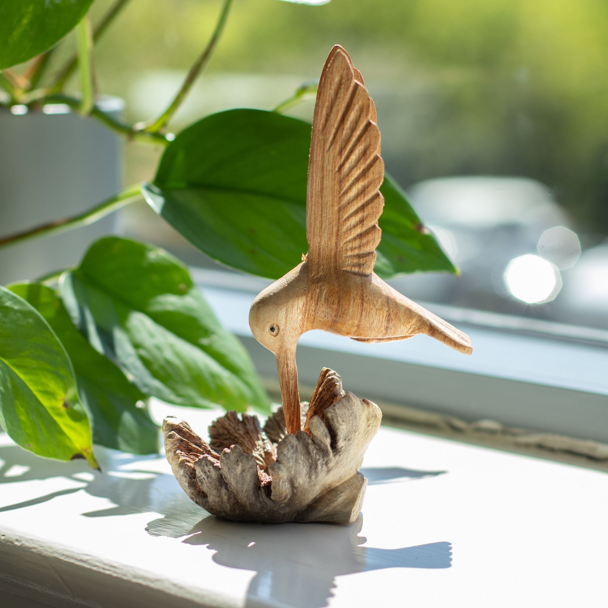 Håndlavet skulptur af en kolibri, der drikker nektar fra træknopper