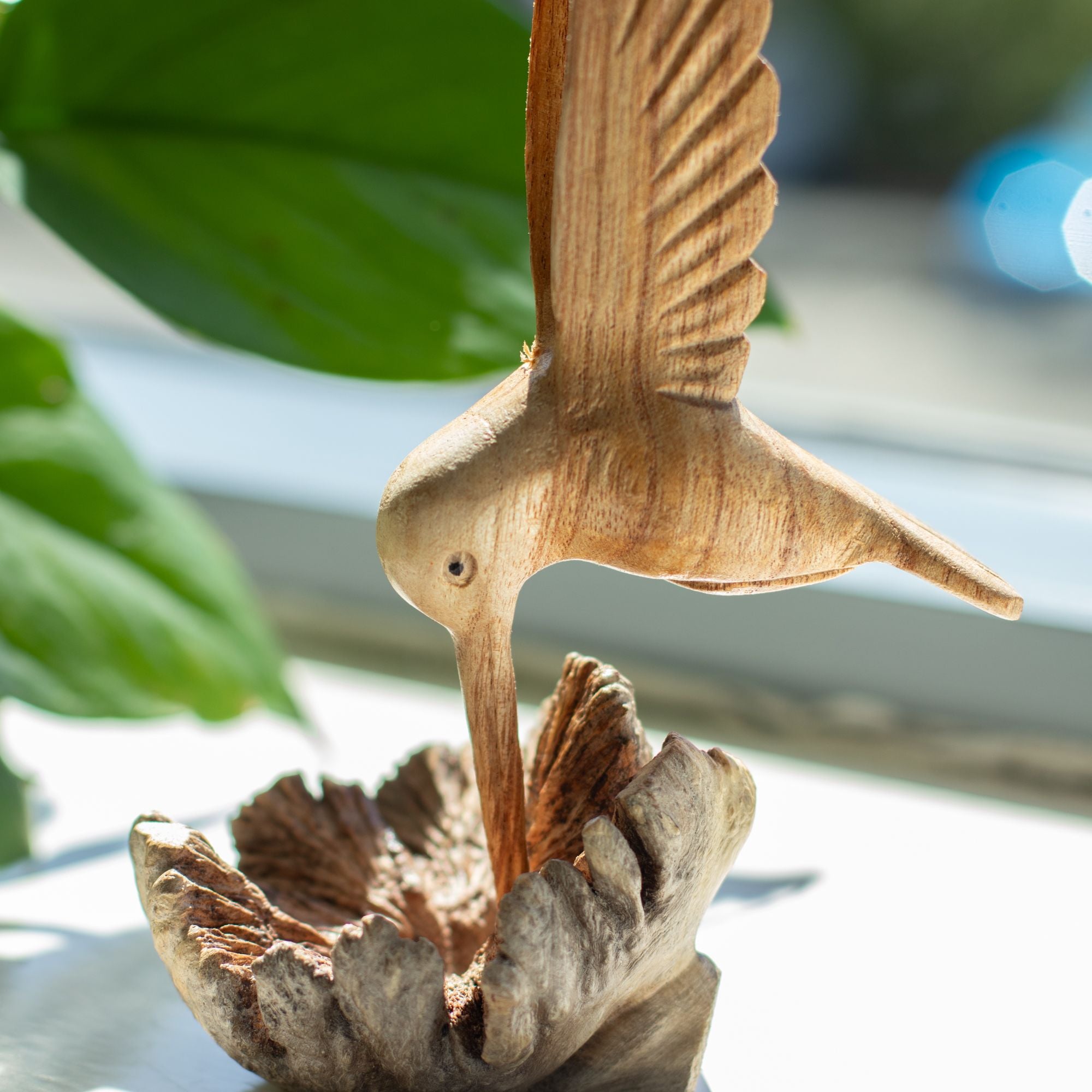 Håndlavet skulptur af en kolibri, der drikker nektar fra træknopper
