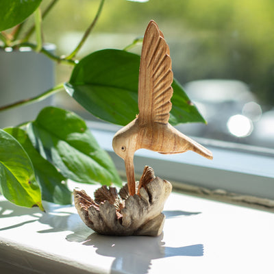 Håndlavet skulptur af en kolibri, der drikker nektar fra træknopper
